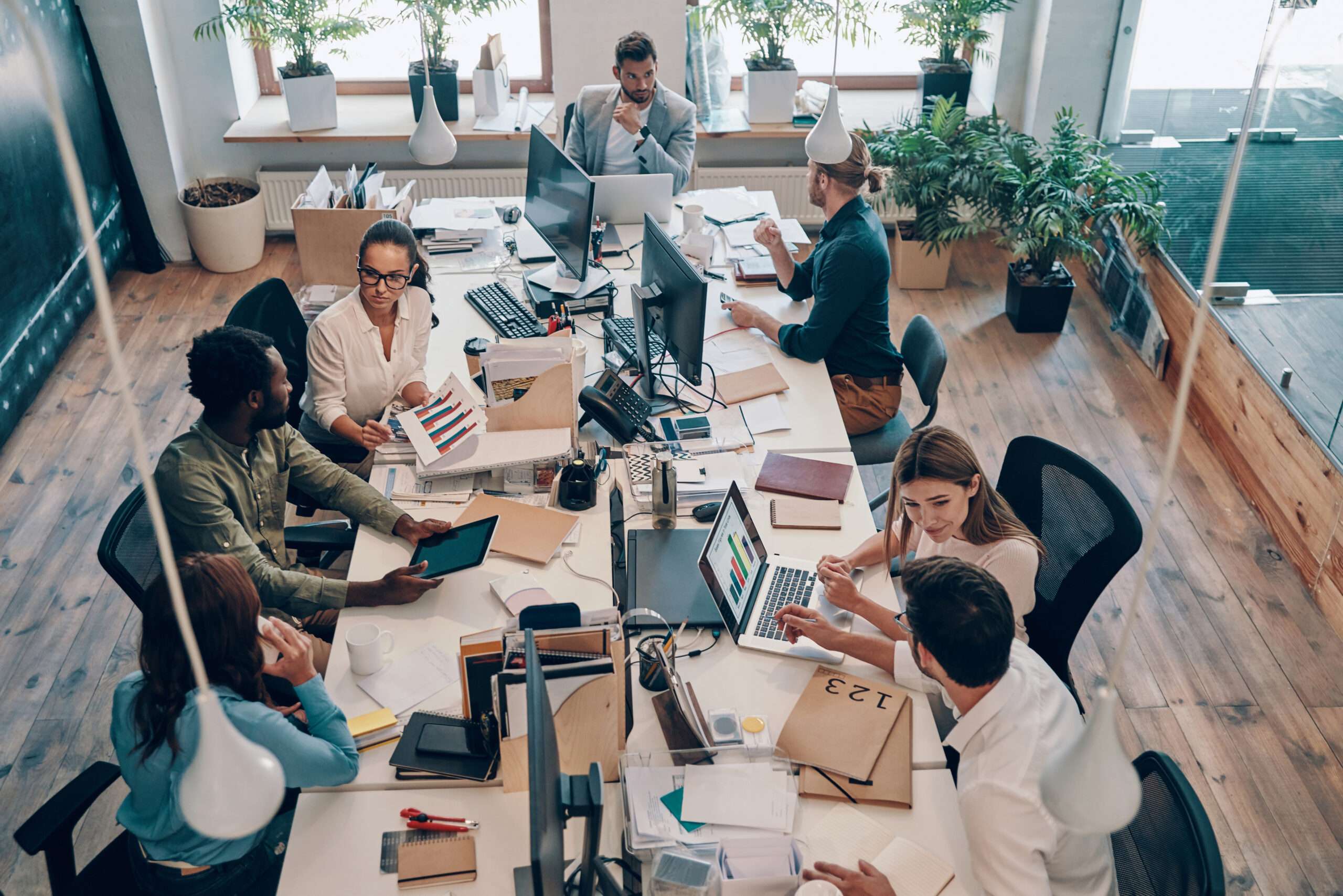 Top view of young modern people in smart casual wear communicating and using modern technologies while working in the office