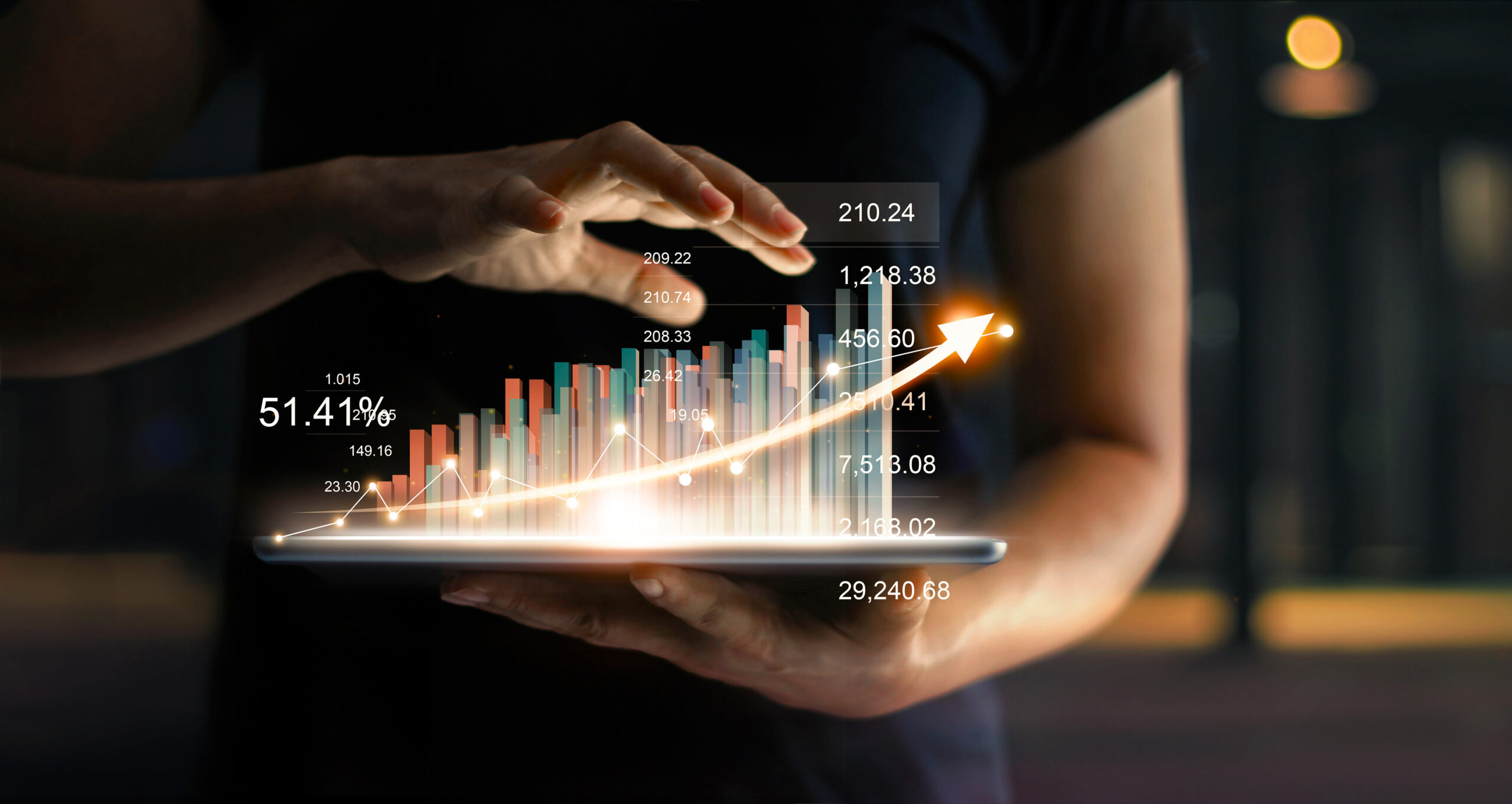 Marketer holding tablet and showing a growing virtual hologram of statistics, graph and chart with arrow up on dark background. Business growth, planning and strategy concept.