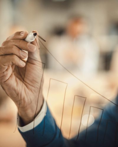 Close up of a businessman drawing diagram of progress on a glass wall.